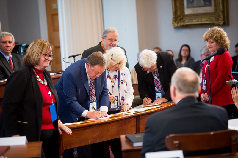 a group of people signing papers.